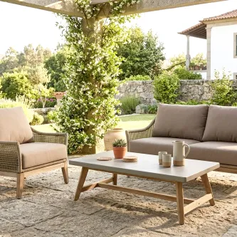 Mesa de centro Atesso em madeira sintética num pátio de jardim com sofá e poltrona