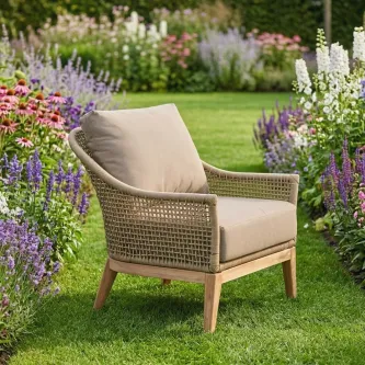 Poltrona de jardim Atesso em rattan sintético com almofada bege em relvado florido