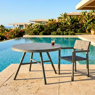 Mesa de jardim Cube redonda junto à piscina com cadeira e copo
