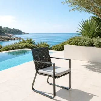 Cadeira de jardim com braços Star em metal escuro com almofada junto a piscina e vista mar