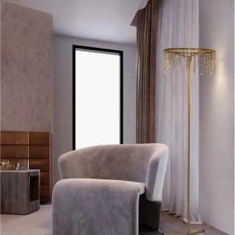 Candeeiro de pé dourado com pendentes em cristal ao lado de poltrona cinzenta