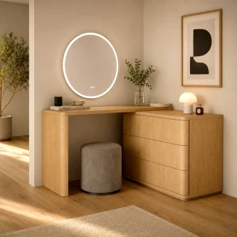 Secretária com cómoda em madeira clara, espelho circular iluminado e banco cinzento.