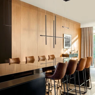 Candeeiro de teto Elettra preto e linear sobre ilha de cozinha com bancos altos