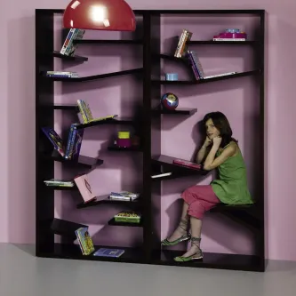 Biblioteca Sette estante escura com prateleiras assimétricas, livros e mulher sentada
