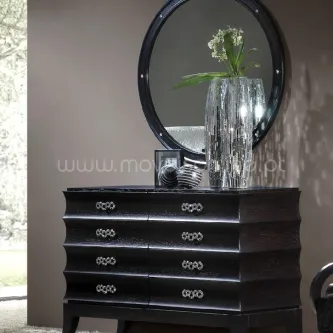 Cómoda preta com gavetas curvas, espelho redondo e vaso decorativo prateado