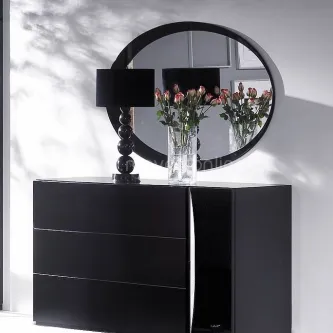 Cómoda preta com espelho redondo, candeeiro e vaso com flores