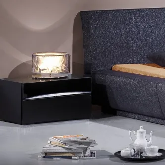 Mesa de cabeceira preta lacada com uma gaveta, candeeiro translúcido e cama ao lado