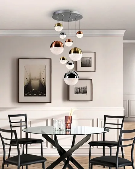 Candeeiro de teto Sphere App com esferas metálicas pendentes sobre mesa de jantar