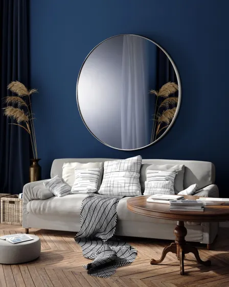 Espelho Orio redondo com moldura metálica sobre sofá cinzento e mesa de madeira