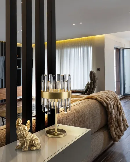 Candeeiro de mesa Grace dourado com pendentes de cristal sobre consola junto a estatueta de cão