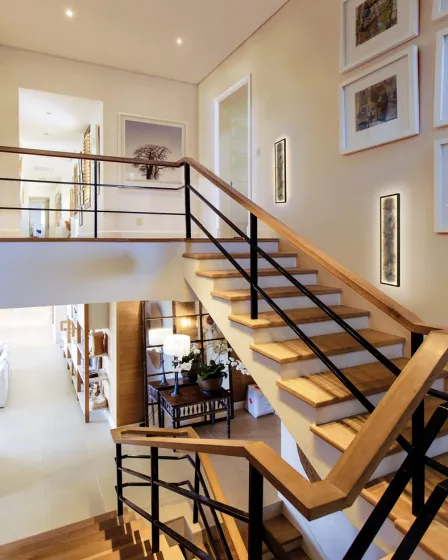 Aplique Stone L60 vertical iluminado numa parede junto a escadaria moderna