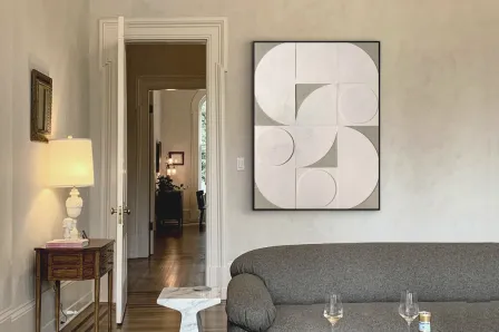 Quadro Geomia com formas geométricas brancas e cinzentas numa sala com sofá cinzento