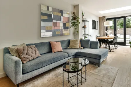 Pintura Zonas abstrata com blocos coloridos, pendurada sobre sofá cinzento numa sala