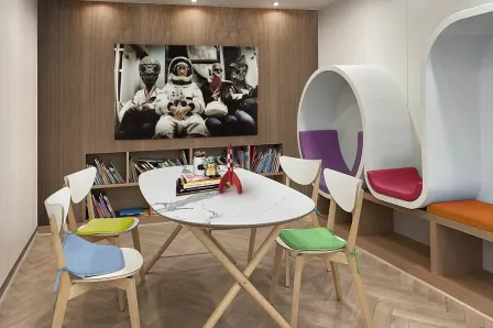 Quadro galaticos com astronauta e figuras extraterrestres numa sala com mesa e cadeiras coloridas