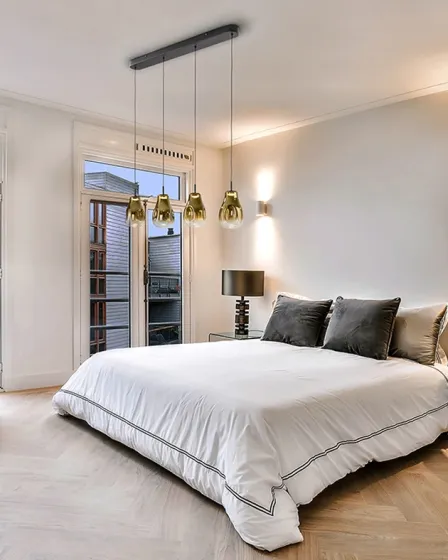 Candeeiro de teto Aledis com três pendentes dourados sobre cama de quarto moderno