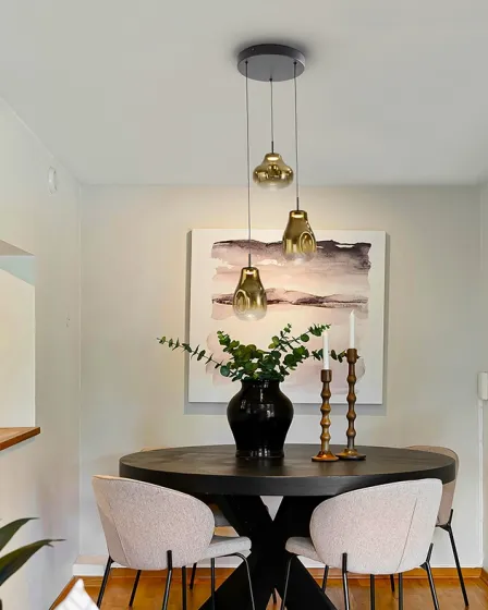 Candeeiro de teto Aledis 3L com três pendentes dourados sobre mesa de jantar