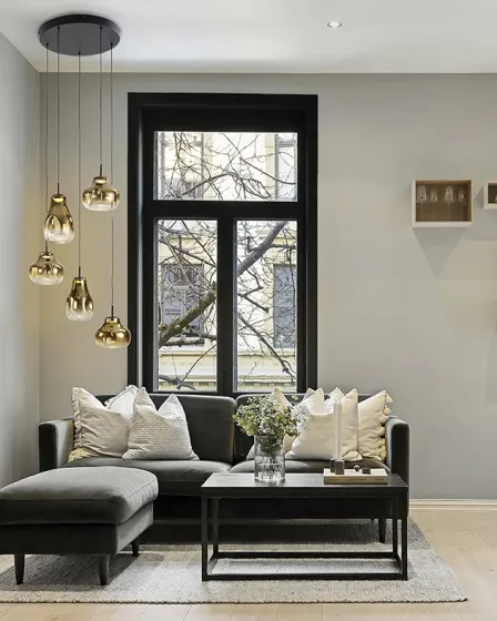 Candeeiro de teto Aledis 5L dourado com cinco pendentes sobre sofá numa sala moderna