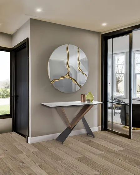 Consola Noa com tampo triangular e pernas metálicas em X junto a espelho redondo