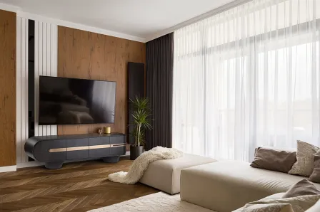 Móvel TV Luca Ouro Rosa contra parede de madeira numa sala com sofá e cortinas