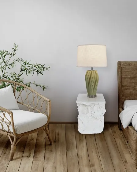 Mesa de apoio Block branco esculpido com candeeiro verde entre cama e cadeira rattan