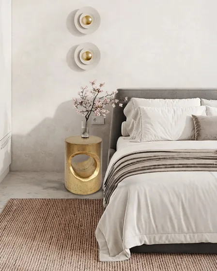 Mesa de apoio Hole dourada com abertura circular ao lado de cama minimalista