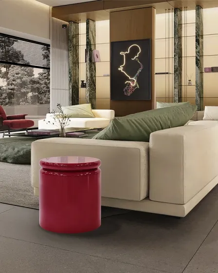 Mesa de apoio Nola vermelha cilíndrica brilhante junto a sofá branco em sala moderna