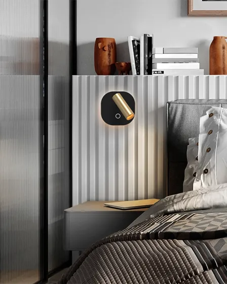 Aplique Biblos preto e dourado montado na parede junto à cabeceira da cama