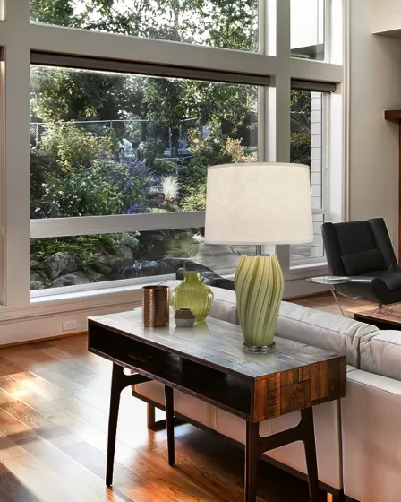 Candeeiro de mesa Salome com base verde estriada e cúpula branca numa consola de madeira