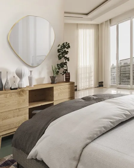 Espelho de forma orgânica com moldura dourada sobre móvel de madeira num quarto luminoso