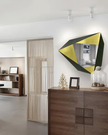 Espelho facetas geométrico dourado e preto pendurado acima de cómoda em sala moderna