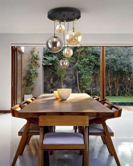 Candeeiro de teto com cinco globos de vidro pendentes sobre mesa de jantar em madeira
