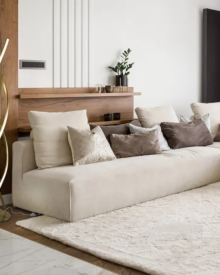 Candeeiro de pé Dido curvo ao lado de sofá bege numa sala moderna