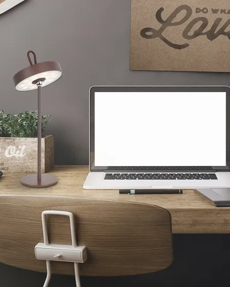 Candeeiro de mesa Gong portátil em metal sobre secretária junto a computador portátil