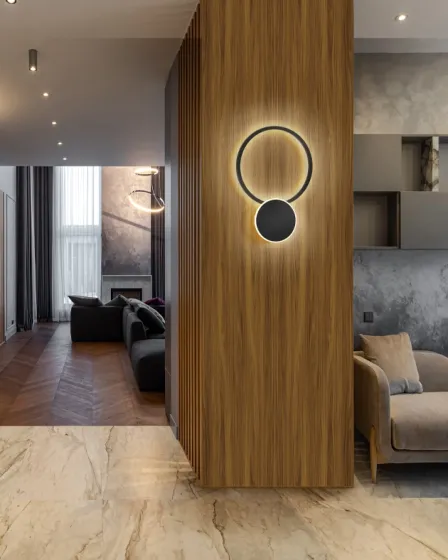 Aplique Omnio redondo com anel luminoso e disco escuro montado em painel de madeira