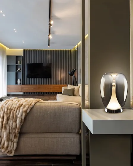 Candeeiro de mesa Suspiro moderno em vidro iluminado sobre mesa lateral numa sala