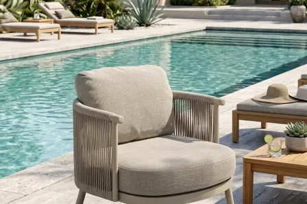 Poltrona de jardim Sabbia junto à piscina com estofos bege e braços em corda.