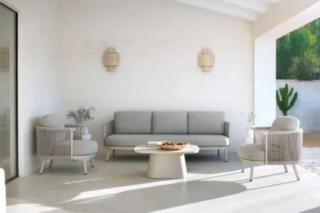 Mesa de centro Jardim Sabbia oval num pátio luminoso com sofá e poltronas