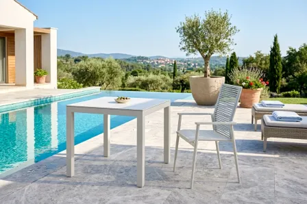 Mesa de jardim Strixe branca junto à cadeira ao lado da piscina