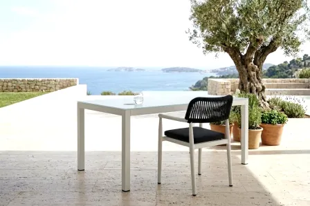 Mesa de jardim retangular Kurve branca com cadeira preta em terraço junto ao mar