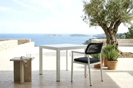 Mesa de jardim quadrada Kurve branca num terraço com cadeira e vista para o mar
