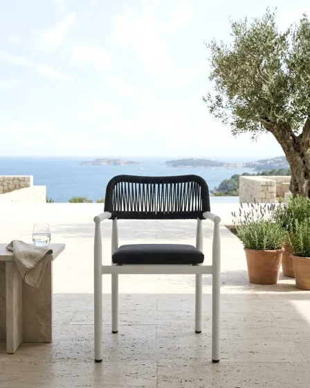 Cadeirão de jardim Kurve com estrutura branca e assento e encosto pretos e vista para o mar