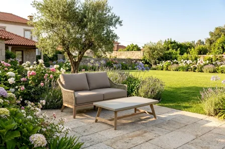 Sofá de jardim Atesso de dois lugares com almofadas e mesa baixa num terraço ajardinado
