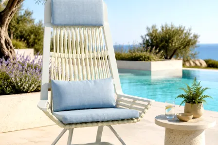 Poltrona relax de jardim branca com cordas e almofadas azuis junto a piscina
