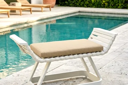 Apoio pés de poltrona Cires branco com almofada bege junto à piscina