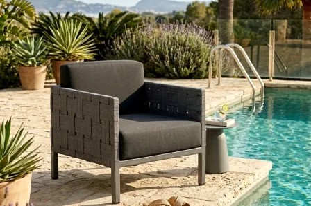 Poltrona de jardim Cube cinzenta junto à piscina com almofadão