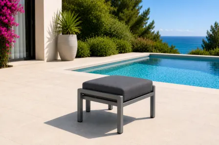 Apoio pés de poltrona Cube em metal cinzento com almofada escura junto a piscina