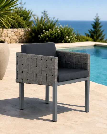 Cadeirão de jardim Cube cinzento com trançado lateral e almofados escuros junto à piscina