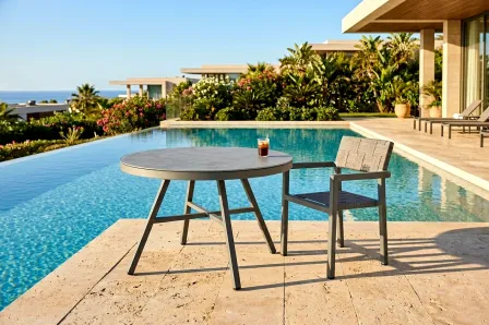 Mesa de jardim Cube redonda junto à piscina com cadeira e copo