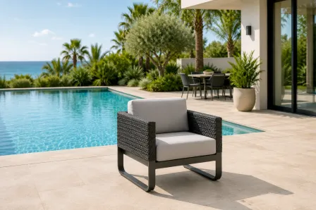 Poltrona de jardim Star em vime sintético escuro com almofadões cinzentos junto à piscina