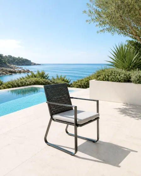 Cadeira de jardim com braços Star em metal escuro com almofada junto a piscina e vista mar
